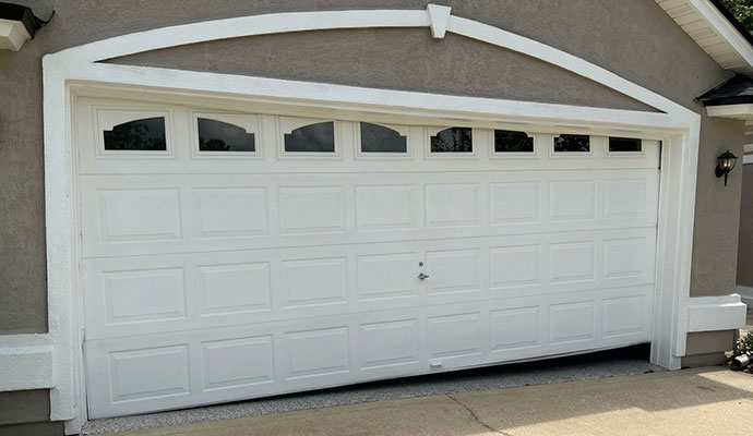 Crooked off-track white garage door with bottom gap