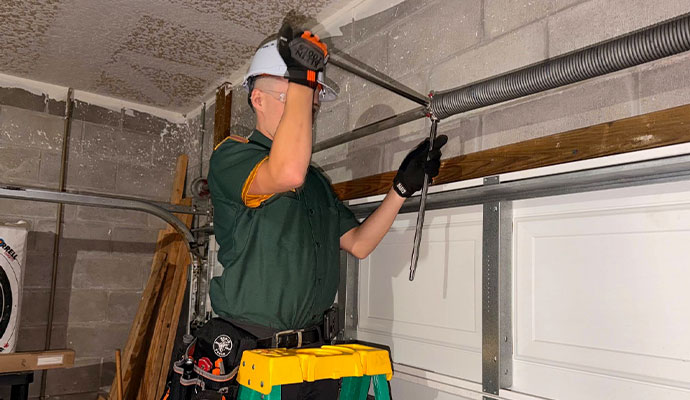 Technician adjusting garage door torsion spring with winding bar