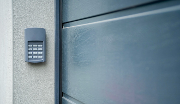 Wireless keypad mounted on exterior wall beside modern garage door