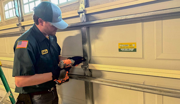 Technician performing preventive garage door maintenance and tightening hardware