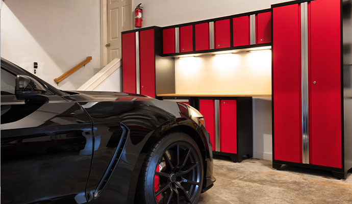 Garage with bold red and black storage cabinets beside a parked car