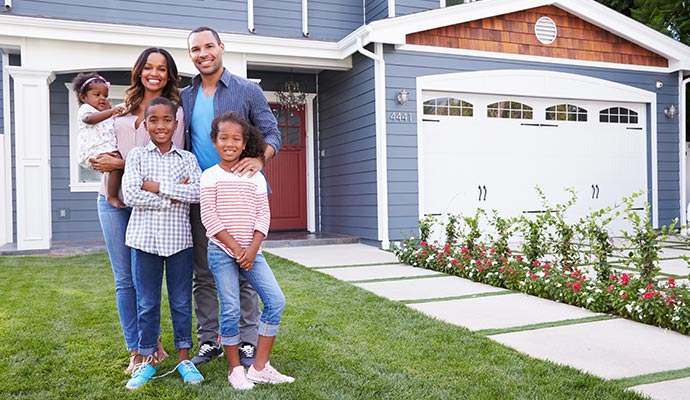 Happy family smiling in front of their modern home
